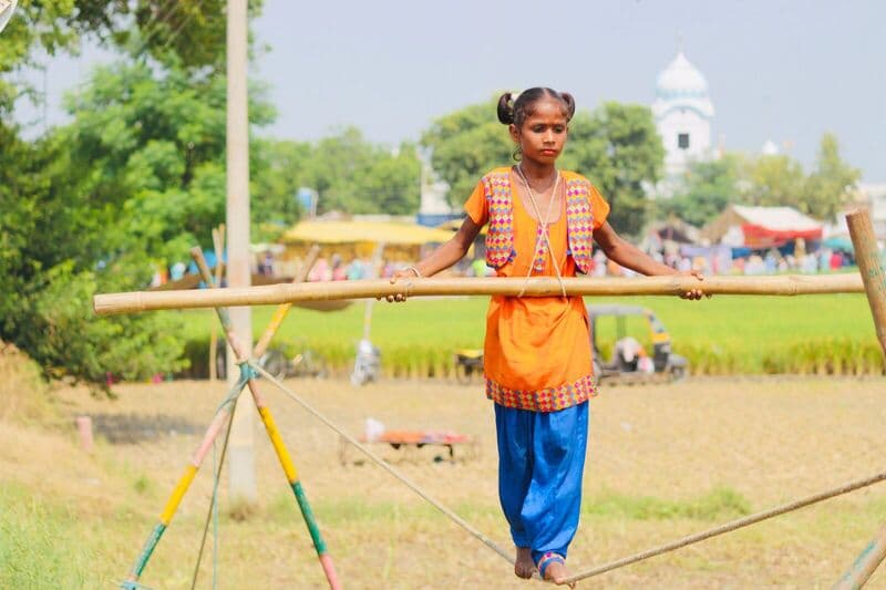 Una ragazzina esegue abilmente un numero di equilibrismo su una fune tesa all'aperto, mostrando il suo talento.