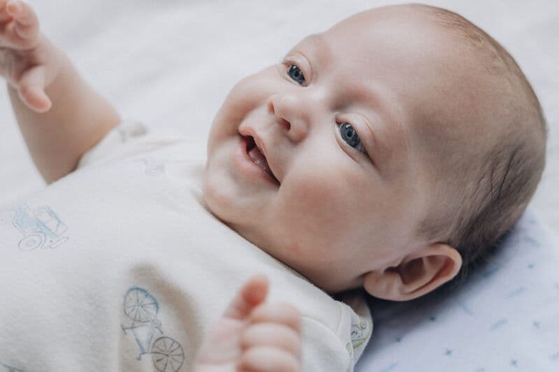 Adorabile bambino sorridente sdraiato su una morbida coperta, che esprime felicità e calore.