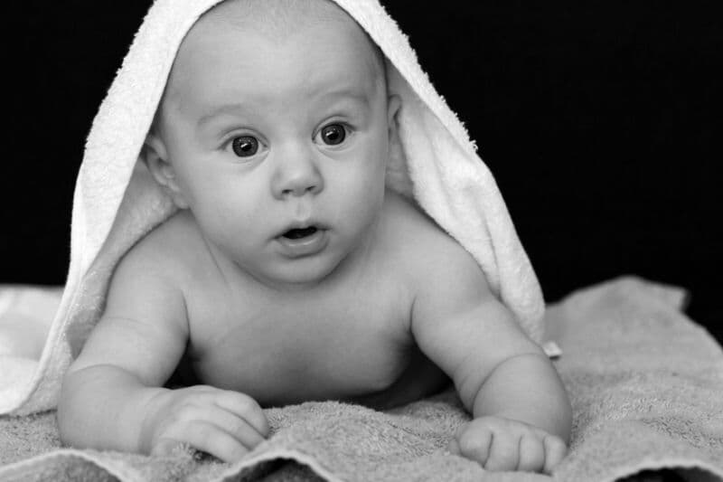 Incantevole ritratto in bianco e nero di un bambino avvolto in un morbido asciugamano, che emana innocenza.