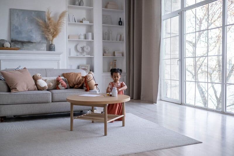 Bambina che gioca in un soggiorno moderno e luminoso con decorazioni accoglienti e giocattoli di peluche.