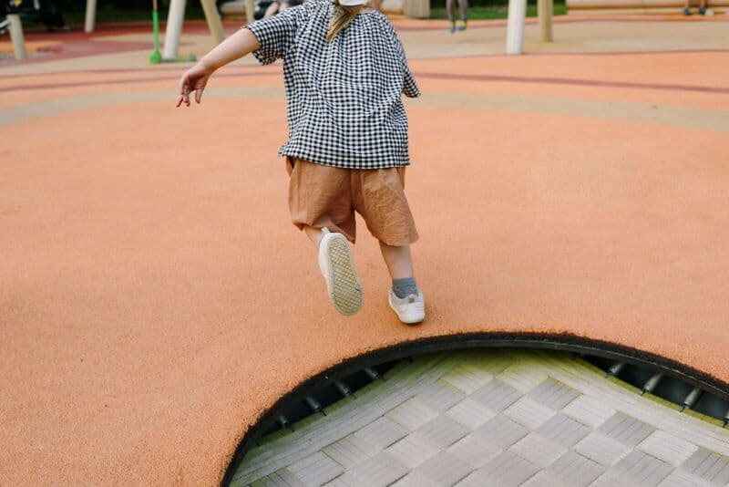 Un bambino giocoso che salta su un trampolino in un parco giochi all'aperto durante l'estate.