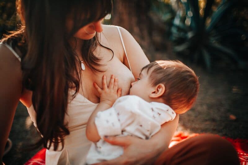 Un momento tenero di una madre che allatta il suo bambino all'aperto alla luce naturale.