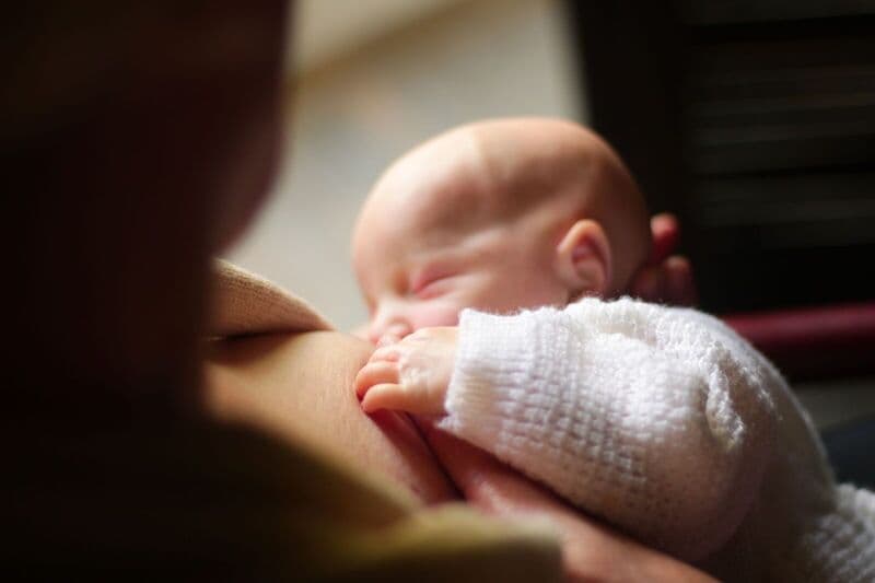 Una vista ravvicinata di una madre che allatta il suo neonato, catturando un momento tenero e intimo.