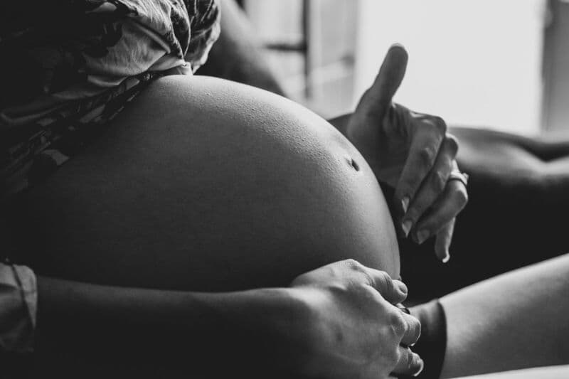 Una serena foto in bianco e nero che cattura il momento di tranquillità di una donna incinta in interni.