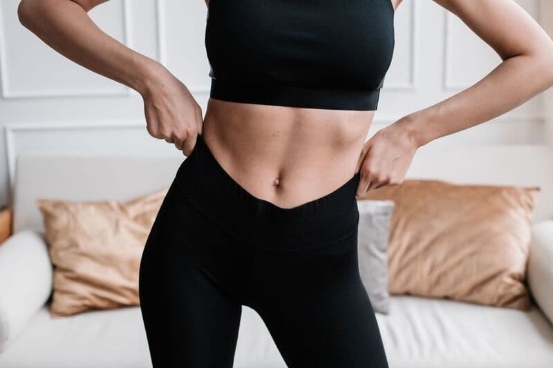 Primo piano di una donna in abbigliamento sportivo che regola i suoi pantaloni in un soggiorno elegante.