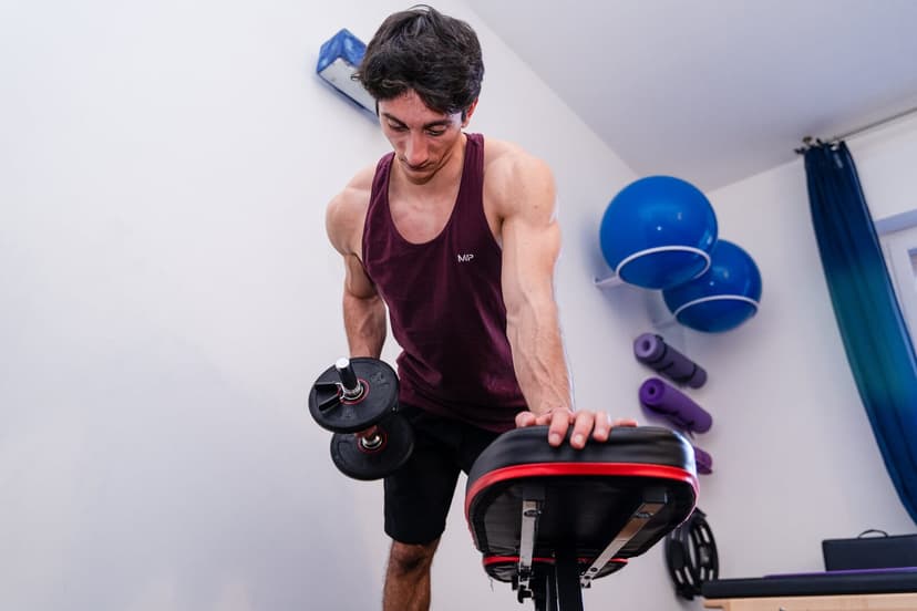 Rematore ripreso frontalmente e dall'alto con il manubrio sul lato sinistro dell'inquadratura, fitball blu appese alla parete