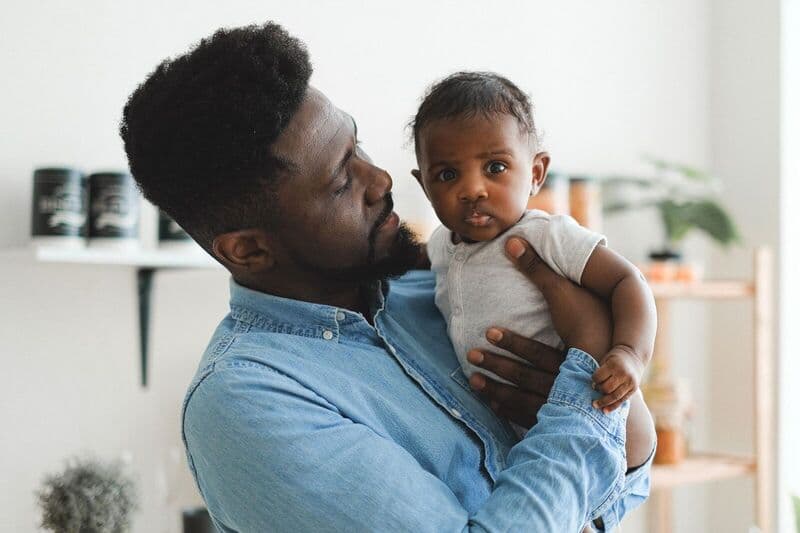 Un padre amorevole che tiene il suo bambino in un ambiente interno accogliente. Momento caldo e tenero.