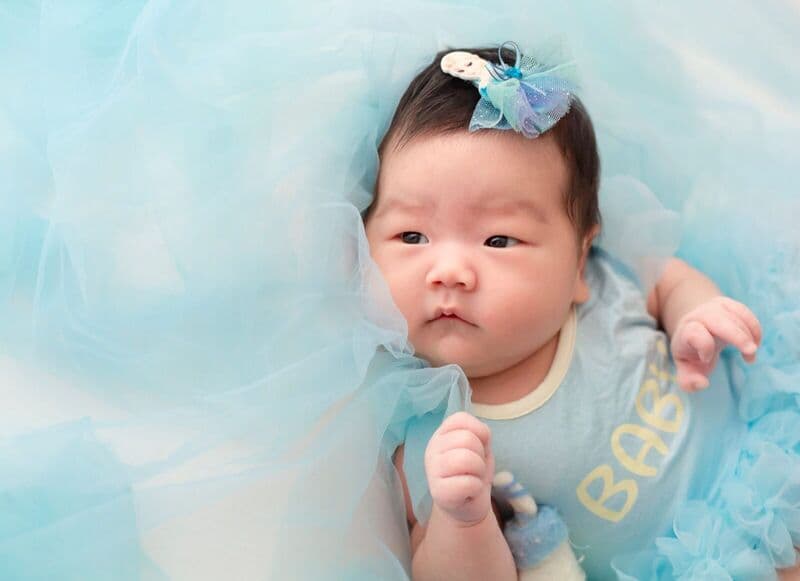 Ritratto affascinante di una bambina in un morbido vestito blu con dettagli in tulle.