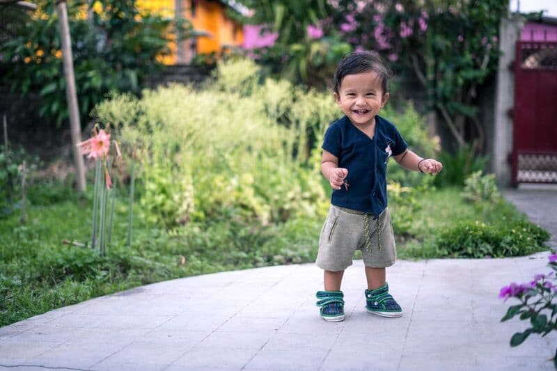 Bambino felice che fa passi all'aperto in un ambiente giardinato vibrante.