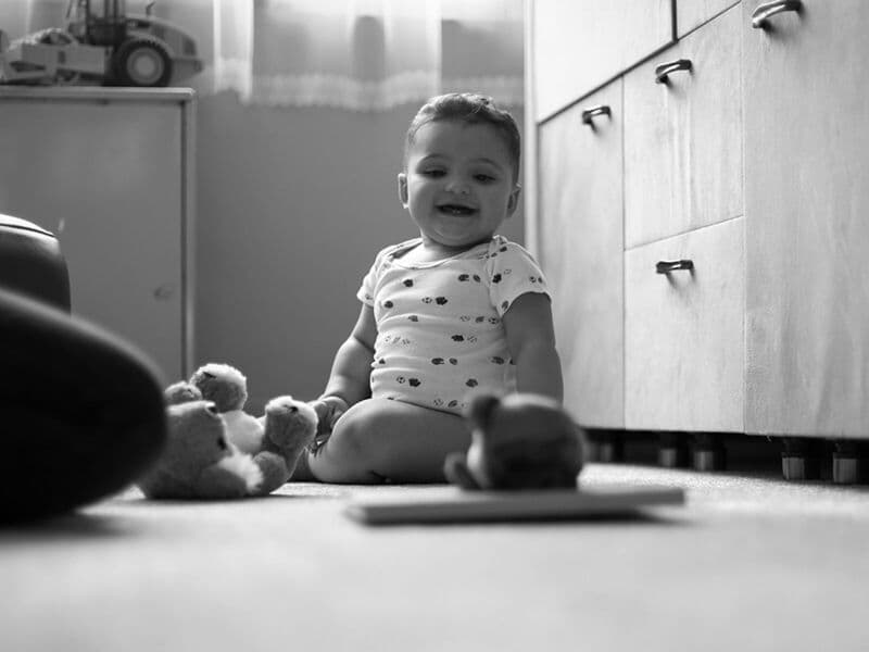Incantevole immagine in scala di grigi di un bambino felice in casa con giocattoli, che mostra innocenza e gioia.