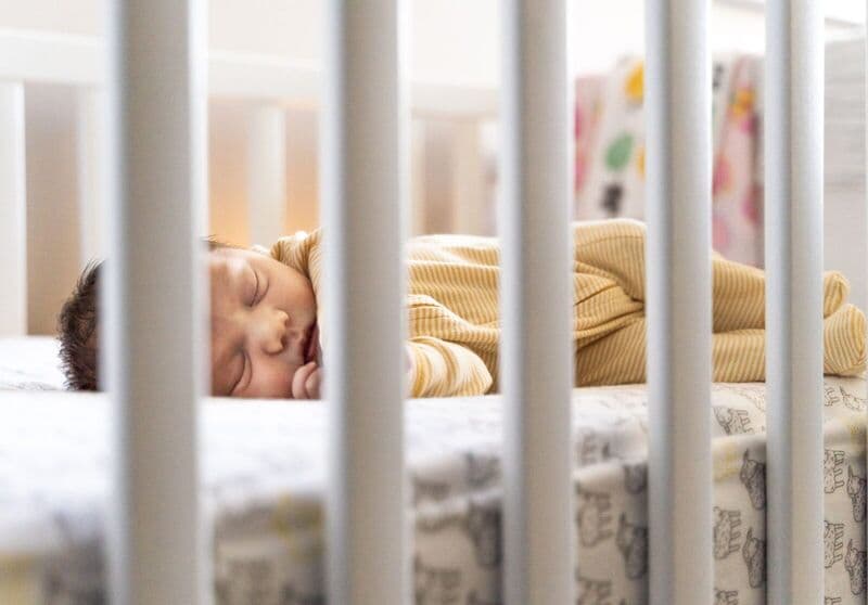 Un'immagine serena di un bambino che dorme pacificamente in una culla, catturando calore e tranquillità.