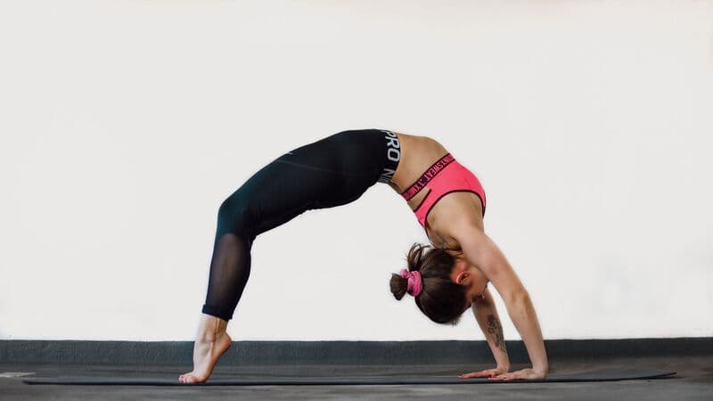 Una donna esegue la posizione del ponte yoga su un tappetino in casa, dimostrando flessibilità e forza.