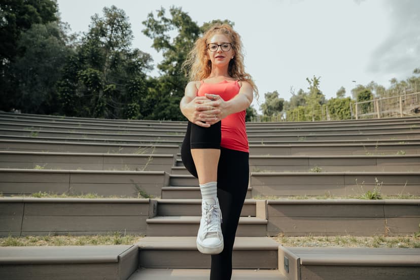 Donna in piedi sulla gradinata di un anfiteatro che porta il ginocchio piegato al petto.