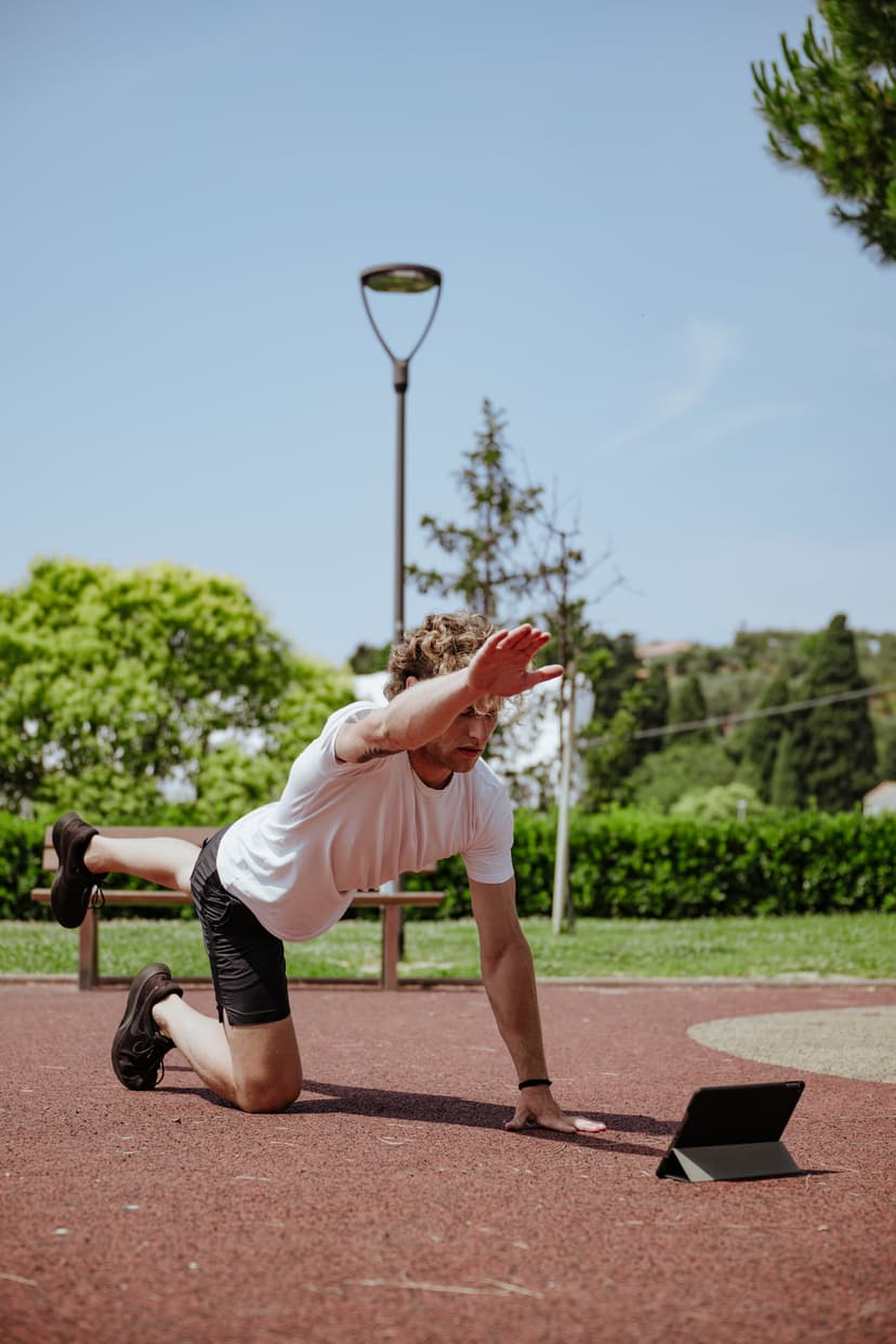 Ragazzo a quattro zampe su una pista d'atletica che esegue il bird dog allungando braccio e gamba opposti