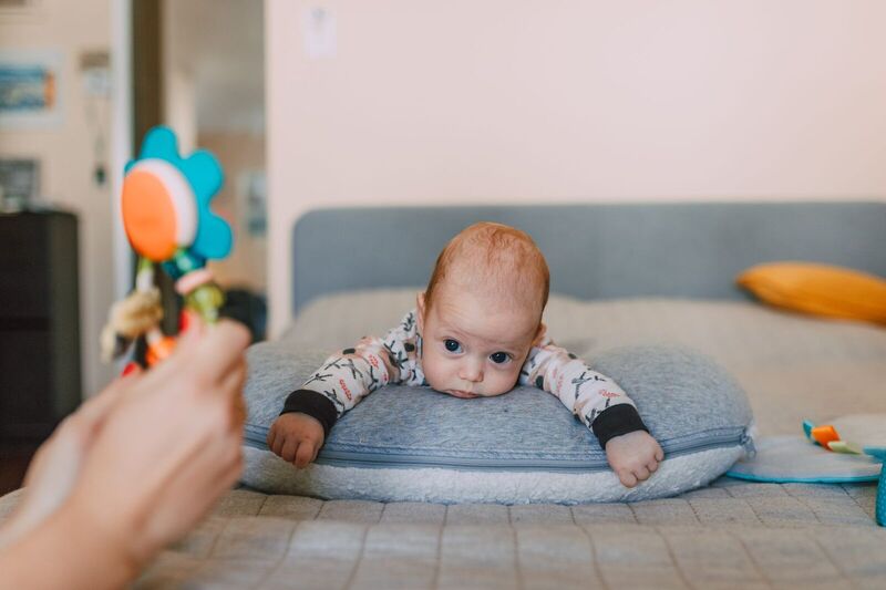Carino bambino a letto che osserva un giocattolo colorato, evocando calore e curiosità.